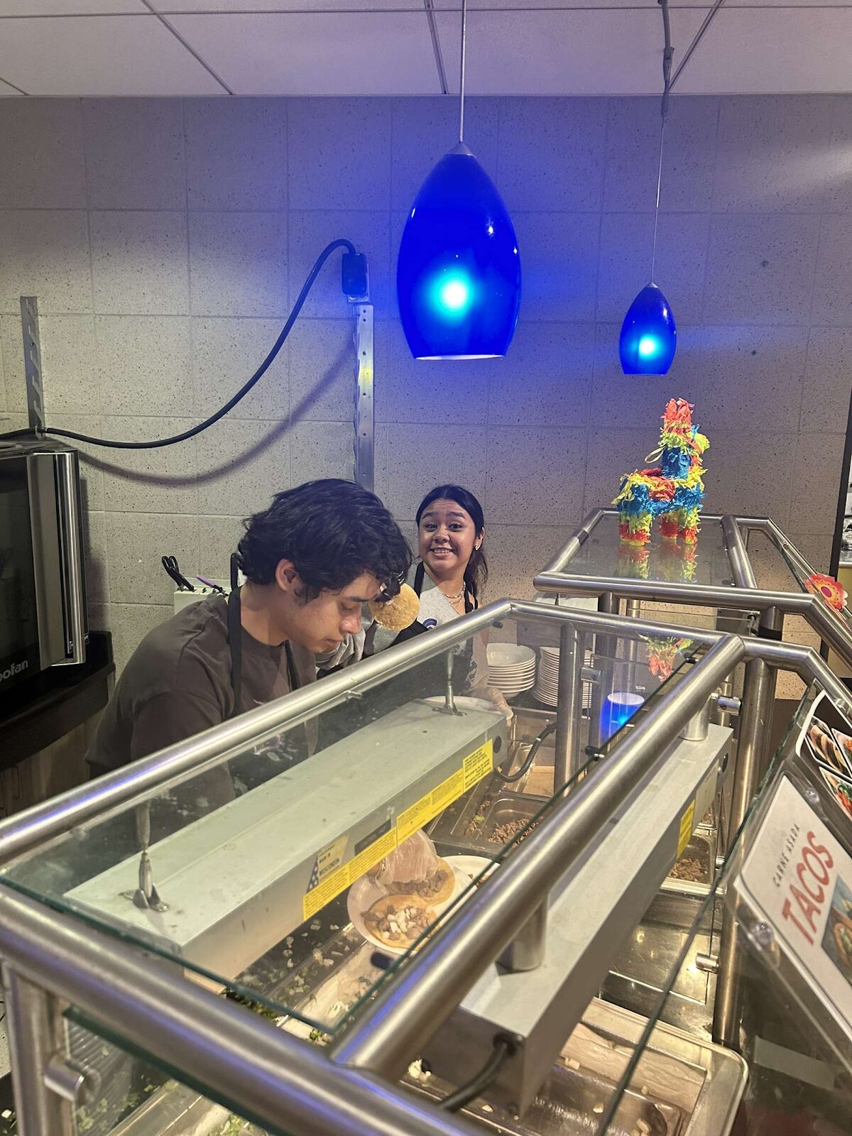 A person and person at a food counter
Description automatically generated